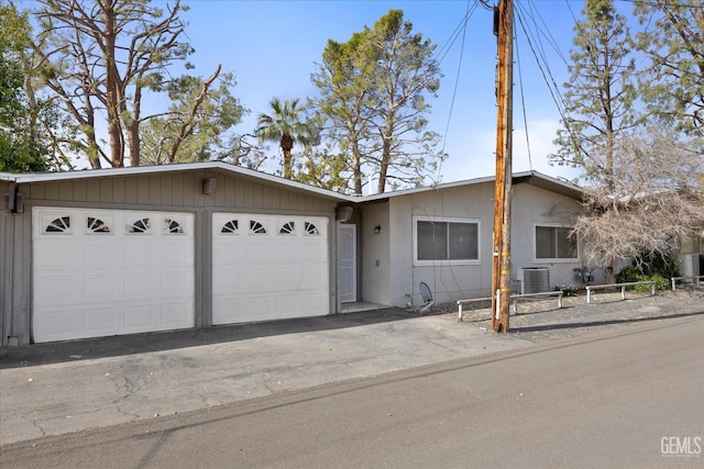 ranch-style house featuring a garage and cooling unit