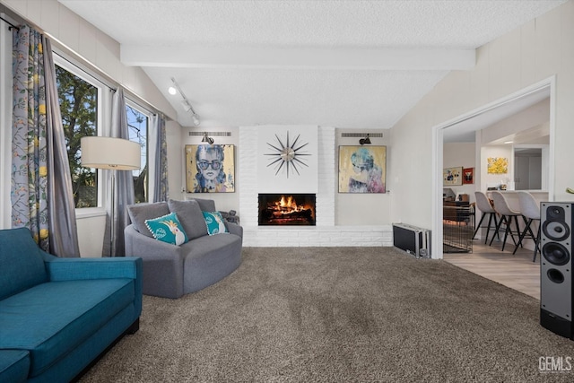 carpeted living room with a brick fireplace, lofted ceiling with beams, and a textured ceiling