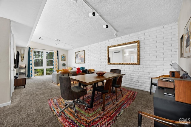 dining space featuring brick wall, rail lighting, a textured ceiling, and dark colored carpet