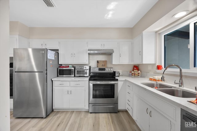 kitchen with stainless steel appliances, white cabinetry, sink, and light hardwood / wood-style flooring