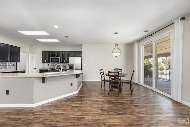 11313 Valletta Ave, Bakersfield, CA 93312 - kitchen with dark cabinets, appliances with stainless steel finishes, decorative backsplash, light countertops, and dark wood-type flooring