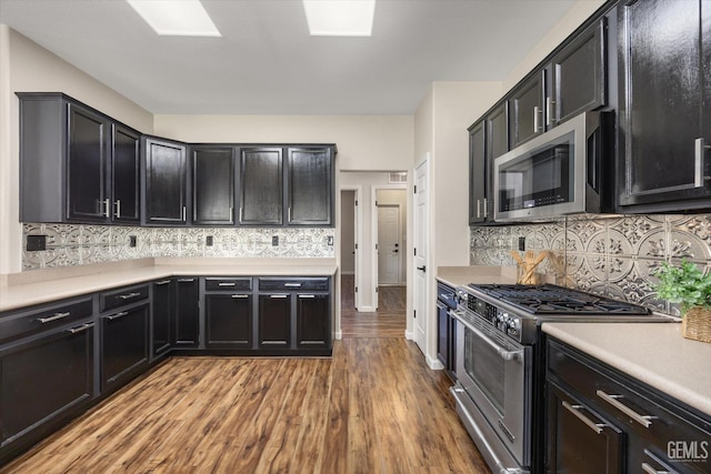 11313 Valletta Ave, Bakersfield, CA 93312 - kitchen with appliances with stainless steel finishes, wood finished floors, light countertops, backsplash, and dark cabinets