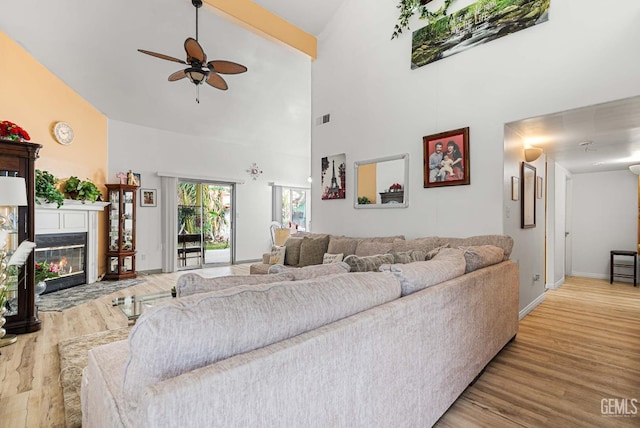 5213 San Martin Dr, Bakersfield, CA 93307 - living area with ceiling fan, wood finished floors, high vaulted ceiling, a fireplace with flush hearth, and baseboards