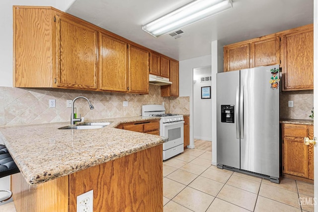 5213 San Martin Dr, Bakersfield, CA 93307 - kitchen with stainless steel fridge, white gas stove, a sink, under cabinet range hood, and a peninsula