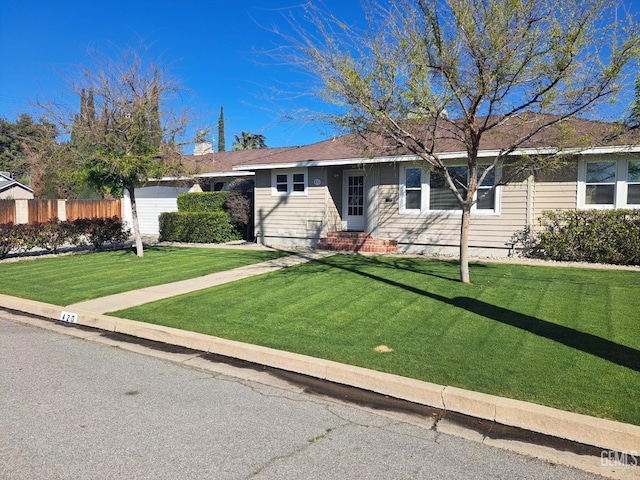 ranch-style home featuring a front lawn and fence