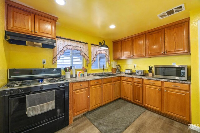 220 Tyler St, Taft, CA 93268 - kitchen with black gas stove, stainless steel microwave, under cabinet range hood, dark wood finished floors, and recessed lighting