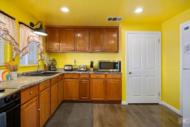 220 Tyler St, Taft, CA 93268 - kitchen featuring stainless steel microwave, dark wood-style flooring, range, brown cabinetry, and recessed lighting