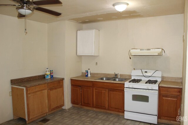 kitchen featuring ventilation hood, ceiling fan, white gas range, and sink