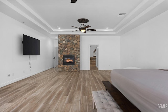 10834 Olcese Rd, Bakersfield, CA 93308 - unfurnished bedroom with hardwood / wood-style flooring, ceiling fan, a stone fireplace, and a tray ceiling