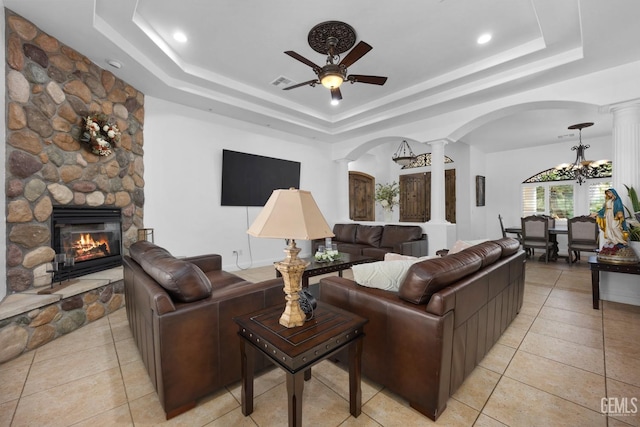 10834 Olcese Rd, Bakersfield, CA 93308 - tiled living room with ceiling fan with notable chandelier, a stone fireplace, a raised ceiling, and ornate columns