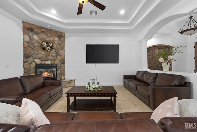 10834 Olcese Rd, Bakersfield, CA 93308 - tiled living room featuring a raised ceiling, decorative columns, a stone fireplace, and ceiling fan