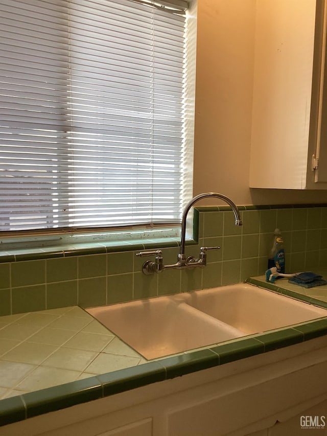 kitchen featuring decorative backsplash, tile counters, white cabinets, and sink