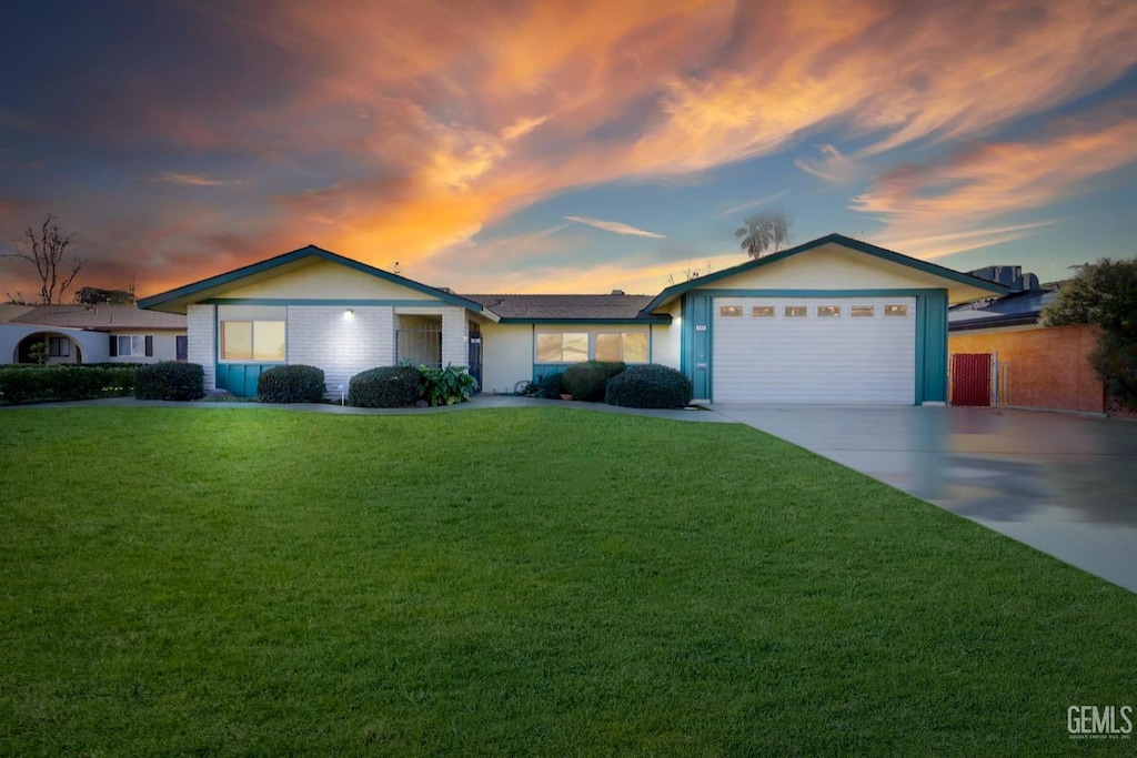 ranch-style house featuring a garage and a lawn