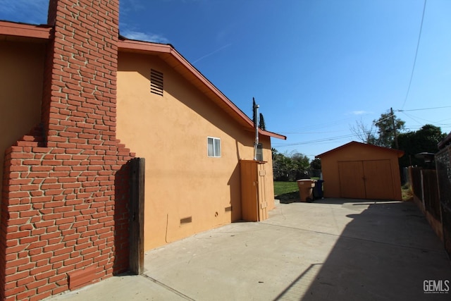 view of side of property featuring a storage shed, an outbuilding, crawl space, a patio area, and stucco siding