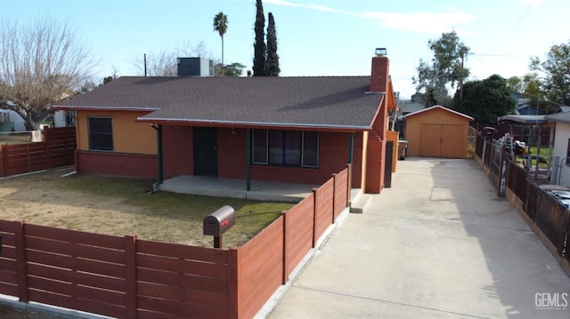 view of front of house with a chimney, fence private yard, a storage unit, an outdoor structure, and brick siding