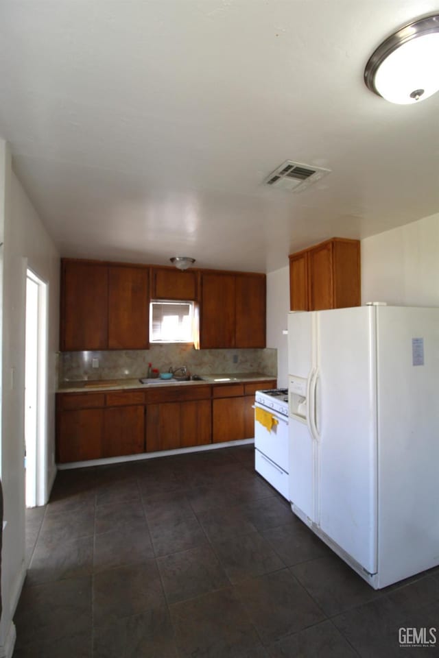 kitchen featuring brown cabinetry, white appliances, light countertops, and visible vents