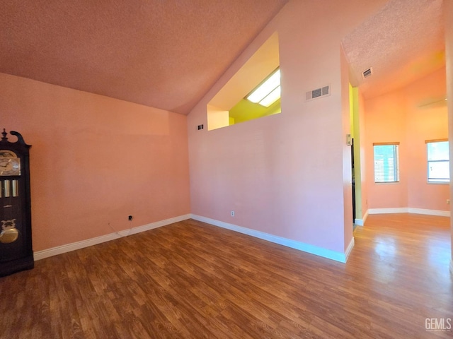 interior space with hardwood / wood-style floors, a textured ceiling, and high vaulted ceiling