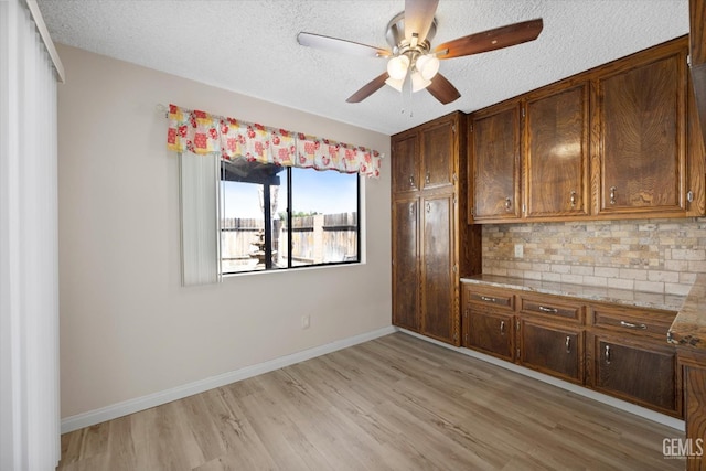 kitchen with tasteful backsplash, ceiling fan, light hardwood / wood-style floors, and a textured ceiling