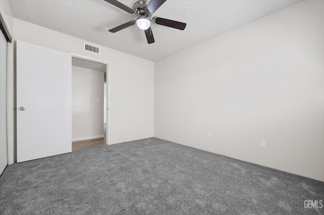 unfurnished bedroom featuring ceiling fan, dark carpet, and a textured ceiling