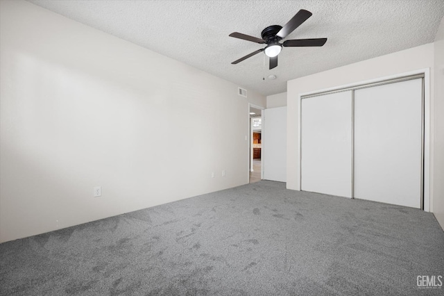 unfurnished bedroom with ceiling fan, carpet floors, a textured ceiling, and a closet