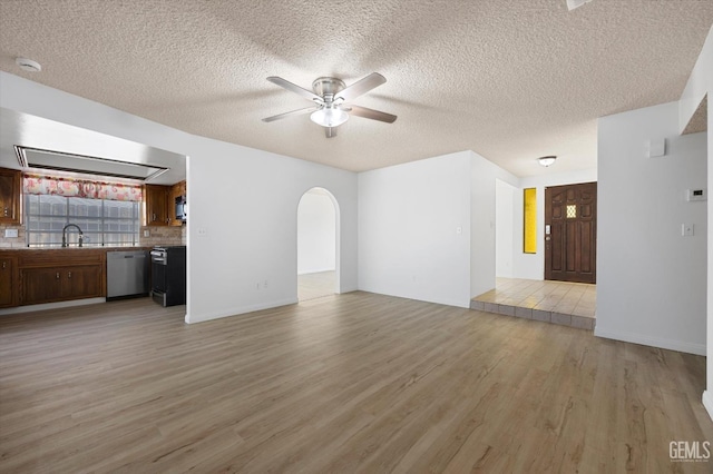 unfurnished living room featuring a textured ceiling, ceiling fan, sink, and light hardwood / wood-style flooring