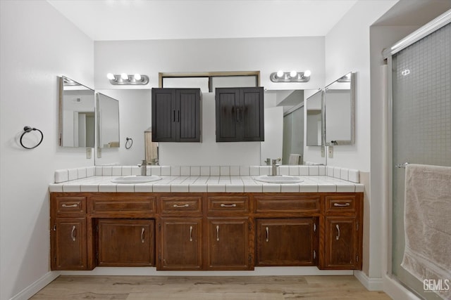 bathroom with hardwood / wood-style floors, vanity, and walk in shower