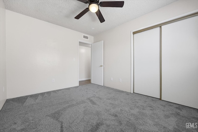 unfurnished bedroom with ceiling fan, a closet, carpet floors, and a textured ceiling