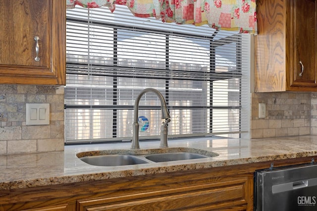 kitchen featuring dishwasher, tasteful backsplash, light stone countertops, and sink