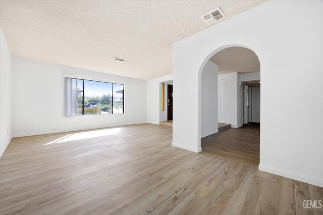 empty room with a textured ceiling and light wood-type flooring