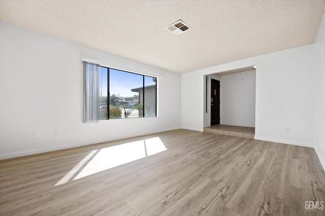 empty room with light hardwood / wood-style floors and a textured ceiling