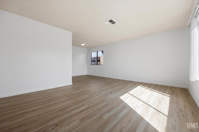 unfurnished room with light hardwood / wood-style floors and a textured ceiling