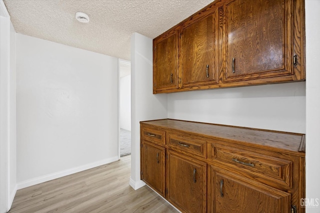 kitchen with a textured ceiling and light hardwood / wood-style flooring