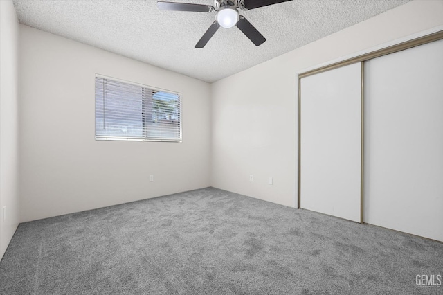 unfurnished bedroom with ceiling fan, a closet, carpet floors, and a textured ceiling