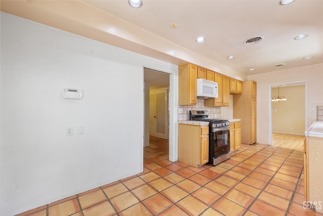 kitchen featuring tasteful backsplash, gas range, recessed lighting, white microwave, and visible vents