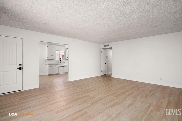 417 B St, Taft, CA 93268 - unfurnished living room with light wood-type flooring and a textured ceiling