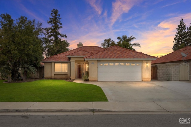 mediterranean / spanish home featuring a garage and a lawn