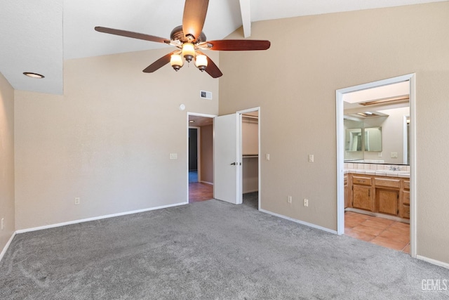 unfurnished bedroom featuring visible vents, a walk in closet, connected bathroom, and light colored carpet