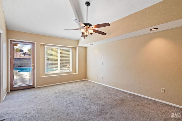 empty room featuring ceiling fan, carpet, lofted ceiling, and baseboards