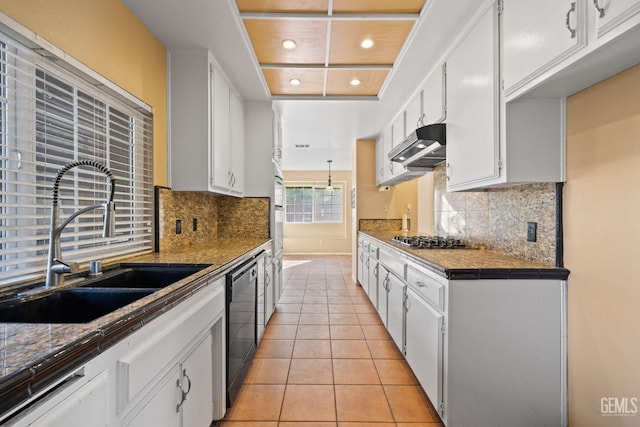 kitchen featuring black dishwasher, dark countertops, white cabinets, a sink, and under cabinet range hood