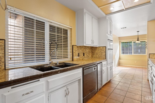 kitchen with pendant lighting, black dishwasher, visible vents, white cabinets, and a sink