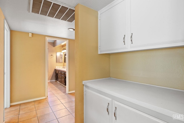 corridor featuring light tile patterned floors, baseboards, and visible vents