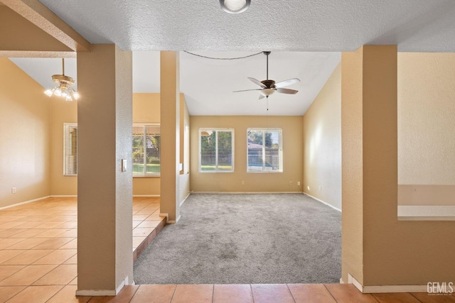 carpeted spare room with lofted ceiling, plenty of natural light, tile patterned flooring, and ceiling fan with notable chandelier