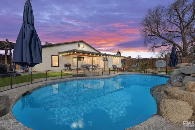 pool at dusk featuring a patio area