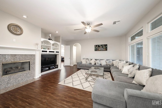 living room with dark hardwood / wood-style flooring, a high end fireplace, and ceiling fan