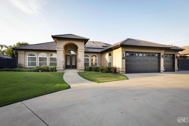 mediterranean / spanish-style home with a garage, a front lawn, and solar panels