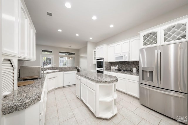 kitchen with white cabinetry, hanging light fixtures, stainless steel appliances, light stone countertops, and a kitchen island