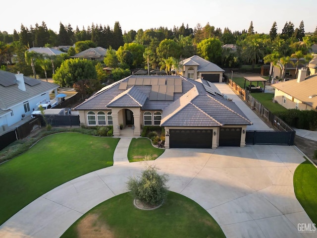 view of front of home with a garage, a front lawn, and solar panels