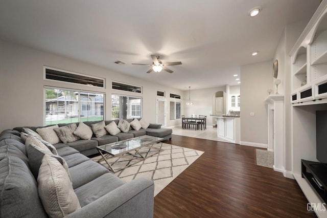 living room with dark hardwood / wood-style flooring, sink, and ceiling fan