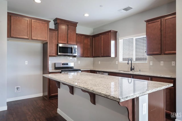 5817 Neutra Dr, Bakersfield, CA 93311 - kitchen with appliances with stainless steel finishes, a kitchen island, recessed lighting, decorative backsplash, and dark wood-style floors