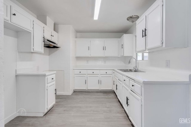 1857 Fern Tree Close, Wasco, CA 93280 - kitchen with under cabinet range hood, white cabinetry, light wood-style flooring, and light countertops